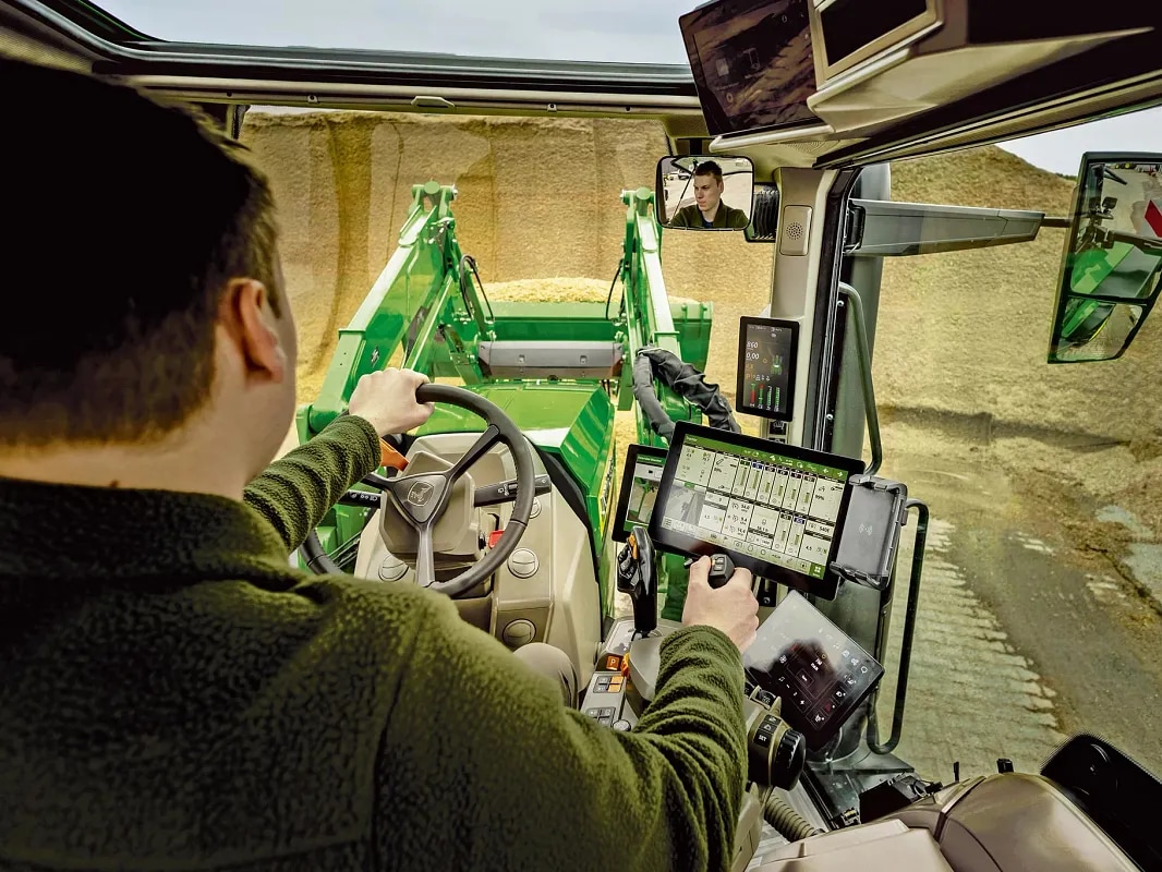 Вътрешен изглед на кабината на трактор John Deere, показващ органите за управление на оператора и работата с челен товарач.