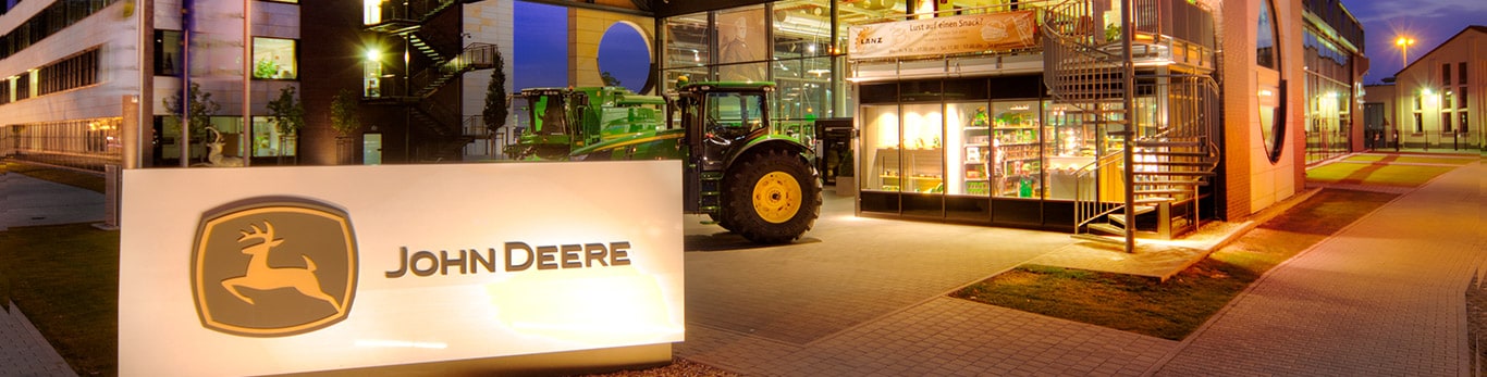 Изглед на фасадата на централата на John Deere с езерото и върбите на преден план