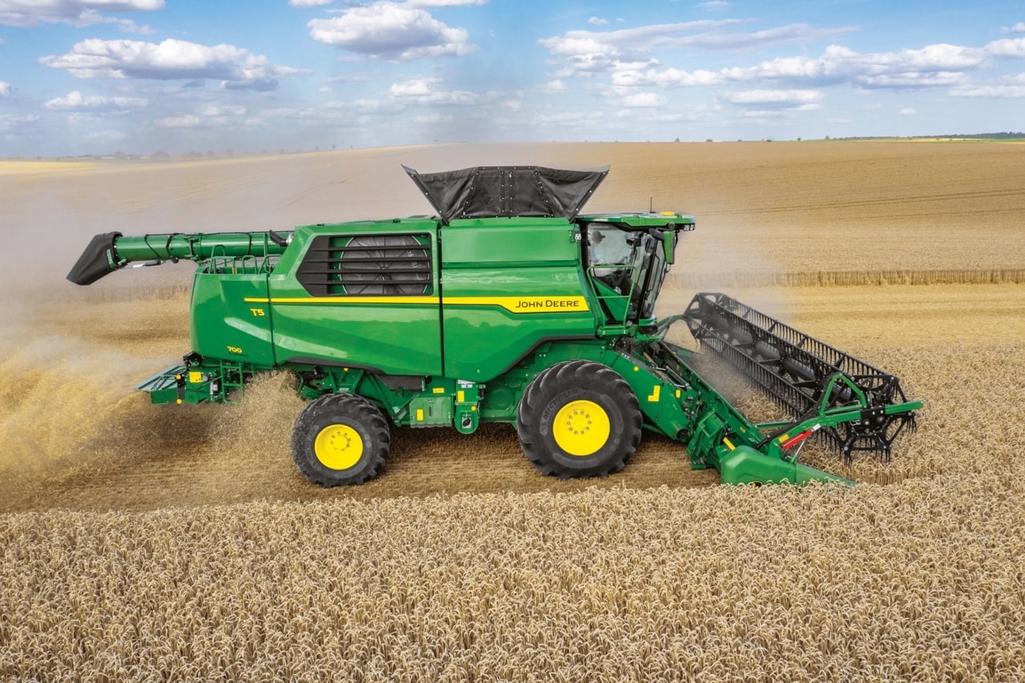 Страничен изглед на комбайна John Deere с режещ хедер за жътва на пшеница в обширни селскостопански полета