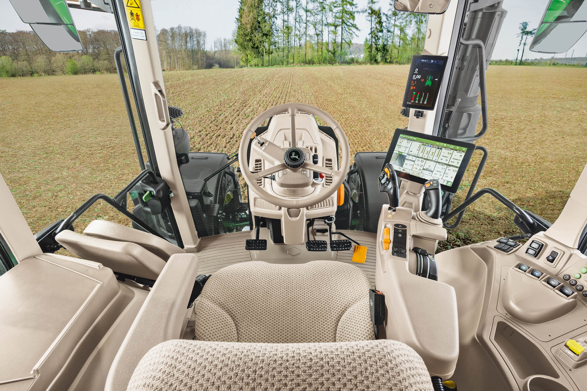 Вътрешен преглед на кабината на трактор John Deere от серия 6M със седалка на оператора, волан и цифрови дисплеи.