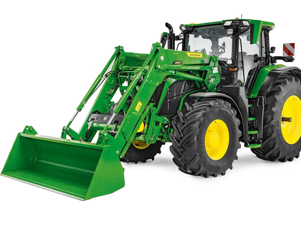 Трактор John Deere с удължен челен товарач и кофа, студийно изображение, което акцентира върху височината на товарача и височина на повдигане.