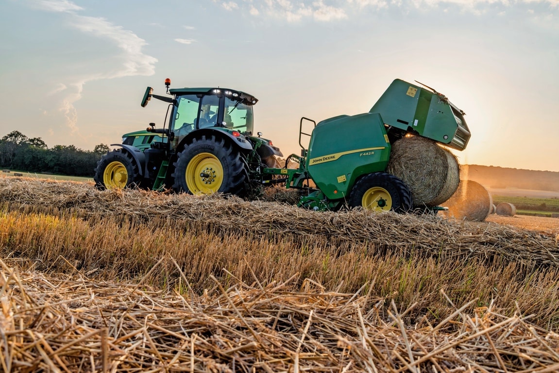 Балопреса John Deere F442M, теглена от трактор John Deere 6M, изхвърляща бала със слама