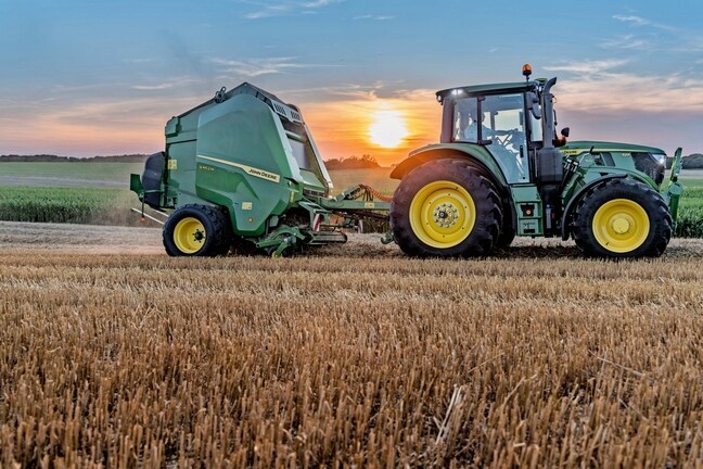 John Deere V462M на сламена нива, теглена от John Deere 6M 150 по залез