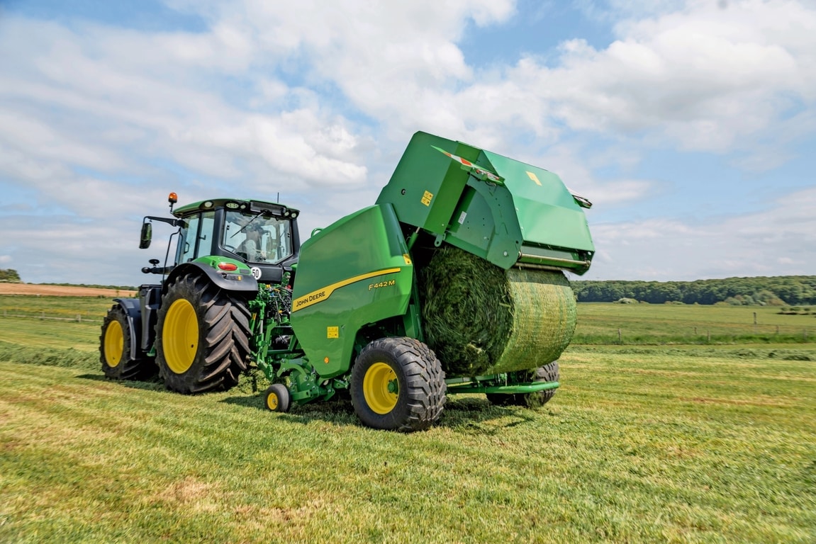 Балопреса John Deere F442M, теглена от трактор John Deere 6M, изхвърляща бала с трева