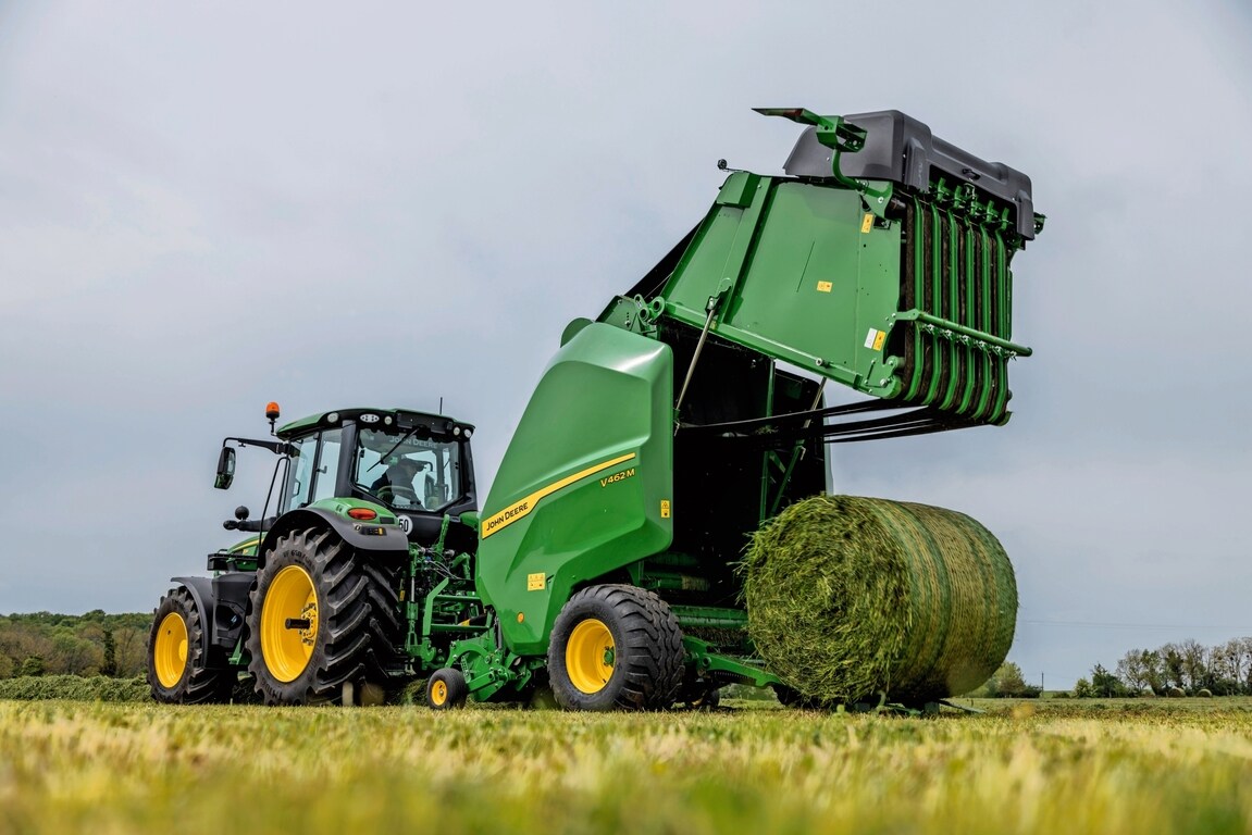 Балопреса John Deere V462M, теглена от трактор John Deere 6M, изхвърляща бала с трева