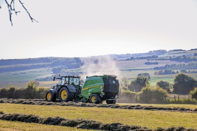 John Deere V462R, теглен от трактор John Deere 6R 185, балиращ сено